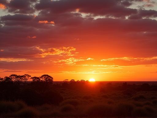 Vast Australian outback landscape at sunset with vibrant orange and purple sky.